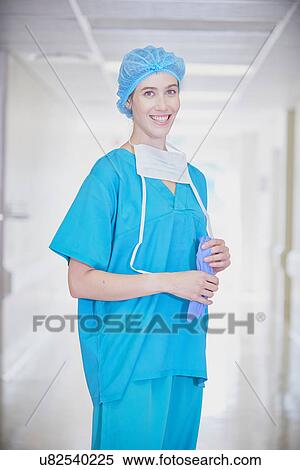 Stock Photography - Portrait of young female medic wearing scrubs in hospital corridor. Fotosearch