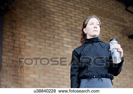 Stock Photo - Portrait of young female runner with bottled water. Fotosearch