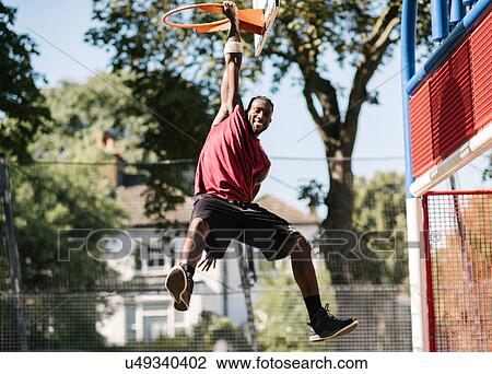 Portrait of young male basketball player hanging from basketball hoop View Large Photo Image Stock Image - Portrait of young male basketball player hanging from basketball hoop. Fotosearch