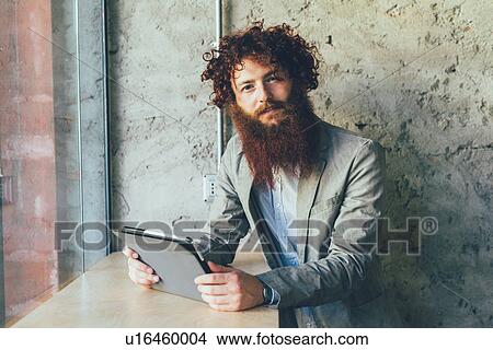 Picture - Portrait of young male hipster with curly red hair and beard in office. Fotosearch