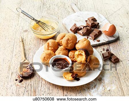 Stock Photo - Profiteroles with hot chocolate sauce, chocolate pieces, egg. Fotosearch