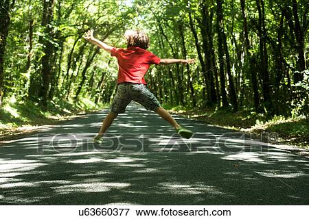 Rear view of boy jumping in mid air View Large Photo Image Stock Photo - Rear view of boy jumping in mid air. Fotosearch