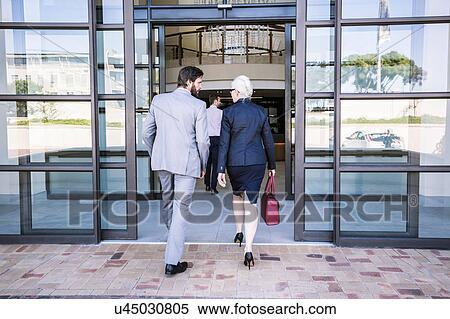 Rear view of businessmen and woman arriving at office building View Large Photo Image Stock Photography - Rear view of businessmen and woman arriving at office building. Fotosearch