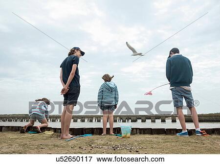 Stock Photo - Rear view of children fishing on pier, Southwold, Suffolk, UK. Fotosearch
