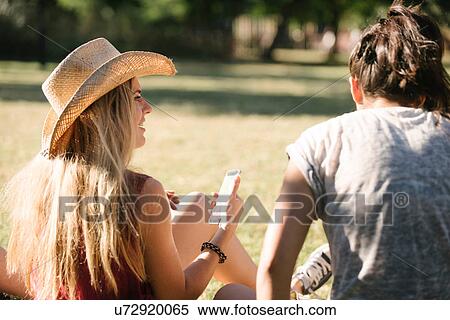 Rear view of female friends chatting in park View Large Photo Image Stock Photography - Rear view of female friends chatting in park. Fotosearch