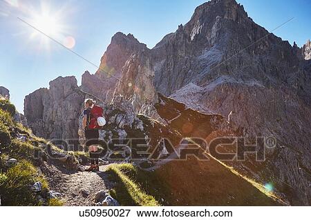 Stock Photo - Rear view of female hiker hiking in Dolomites, Sexten, South Tyrol, Italy. Fotosearch