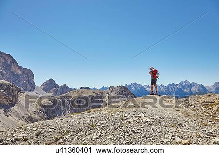 Stock Image - Rear view of female hiker looking out at Dolomites, Sexten, South Tyrol, Italy. Fotosearch