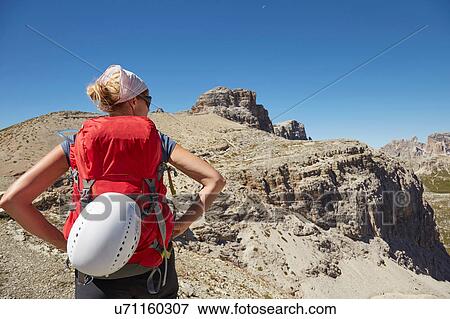 Stock Photo - Rear view of female hiker with hands on hips in Dolomites, Sexten, South Tyrol, Italy. Fotosearch