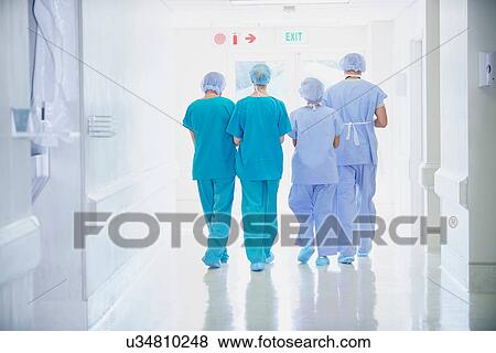 Stock Photo - Rear view of four medical staff wearing scrubs walking in hospital corridor. Fotosearch