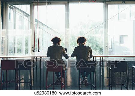 Rear view of male hipster twins working at office desk View Large Photo Image Stock Image - Rear view of male hipster twins working at office desk. Fotosearch