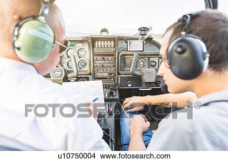 Rear view of pilot and co-pilot sitting in aircraft, talking through flight plan View Large Photo Image Picture - Rear view of pilot and co-pilot sitting in aircraft, talking through flight plan. Fotosearch