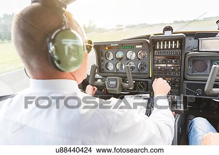 Picture - Rear view of pilot in cockpit of aircraft, in flight. Fotosearch