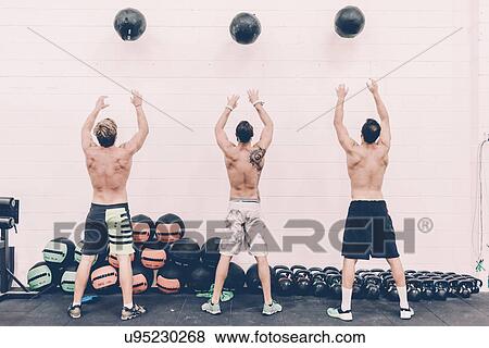 Rear view of three male cross trainers throwing exercise balls in gym View Large Photo Image Stock Photo - Rear view of three male cross trainers throwing exercise balls in gym. Fotosearch