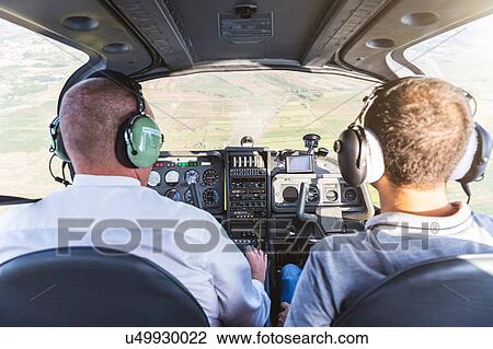 Stock Image - Rear view of two men flying aircraft. Fotosearch