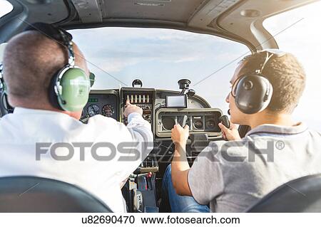 Stock Image - Rear view of two men flying aircraft. Fotosearch