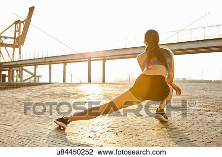 Stock Image - Rear view of woman lunging. Fotosearch