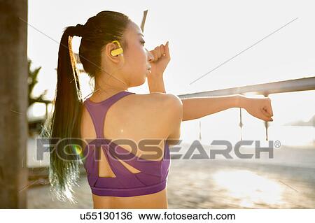 Rear view of woman wearing crop top stretching arm View Large Photo Image Stock Photograph - Rear view of woman wearing crop top stretching arm. Fotosearch