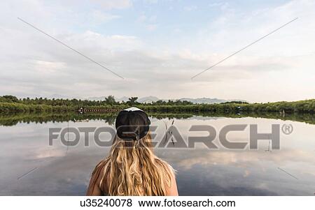 Stock Photo - Rear view of young woman looking out over lake, Gili Meno, Lombok, Indonesia. Fotosearch
