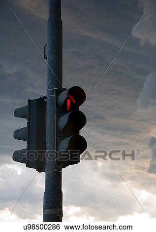 Stock Photograph - Red traffic light on dark cloudy day. Fotosearch
