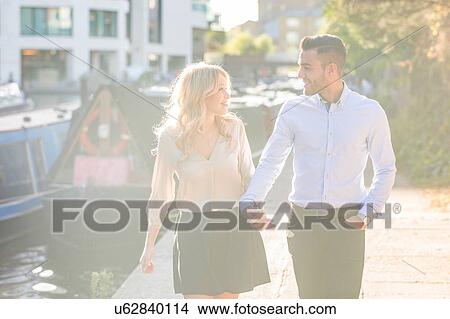 Picture - Romantic young couple holding hands strolling on Regent's Canal, London, UK. Fotosearch