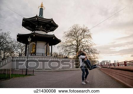 Stock Photo - Romantic young man lifting girlfriend in Battersea Park, London, UK. Fotosearch