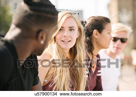 Row of four male and female friends chatting in city skatepark View Large Photo Image Picture - Row of four male and female friends chatting in city skatepark. Fotosearch