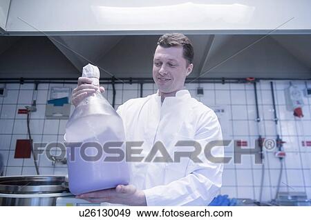 Stock Photo - Scientist carrying large bottle of chemical in laboratory. Fotosearch