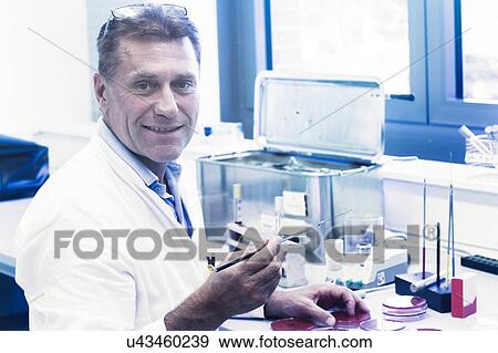 Stock Photo - Scientist examining sample in petri dish. Fotosearch