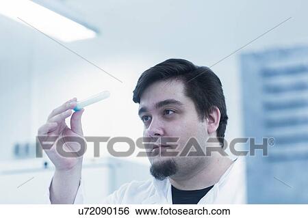 Stock Photograph - Scientist examining sample in test tube. Fotosearch
