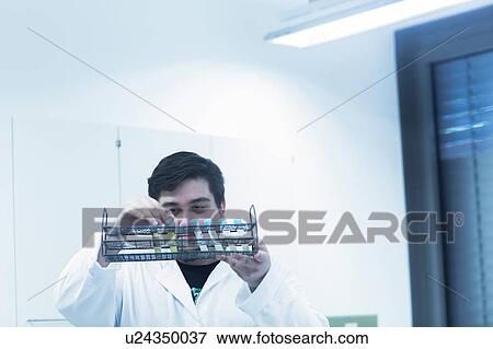 Stock Photo - Scientist examining test tubes in rack. Fotosearch