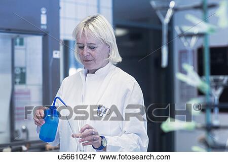 Stock Photo - Scientist pipetting liquid into flask in laboratory. Fotosearch