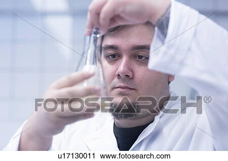 Stock Image - Scientist pipetting sample into beaker in laboratory. Fotosearch