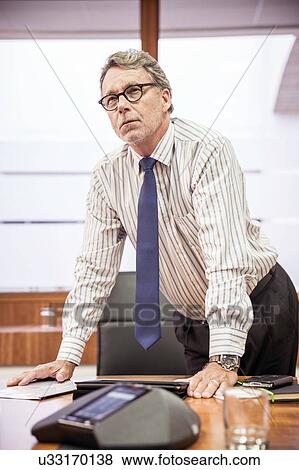 Senior businessman leaning forward on boardroom table View Large Photo Image Stock Photo - Senior businessman leaning forward on boardroom table. Fotosearch