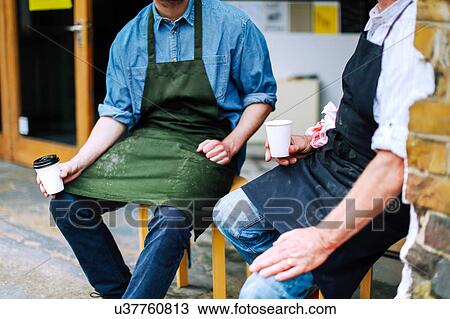 Senior craftsman drinking coffee and chatting to young man outside workshop, mid section View Large Photo Image Stock Image - Senior craftsman drinking coffee and chatting to young man outside workshop, mid section. Fotosearch