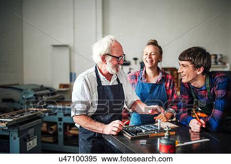 Senior craftsman laughing with young craftsman and craftswoman in letterpress workshop View Large Photo Image Stock Photography - Senior craftsman laughing with young craftsman and craftswoman in letterpress workshop. Fotosearch