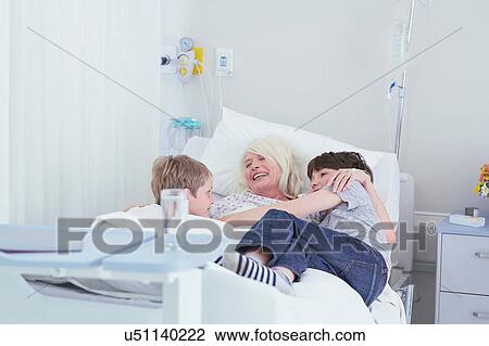 Senior female patient cuddling grandsons on hospital bed View Large Photo Image Stock Image - Senior female patient cuddling grandsons on hospital bed. Fotosearch