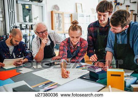 Senior male craftsman brainstorming ideas with group of young men and women in book arts workshop View Large Photo Image Stock Photograph - Senior male craftsman brainstorming ideas with group of young men and women in book arts workshop. Fotosearch
