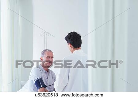 Stock Photo - Senior male patient having blood pressure blood pressure gauge taken by female doctor. Fotosearch