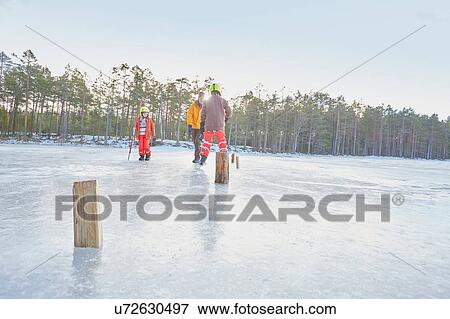 Stock Photo - Senior man and boys practicing ice skating slalom on frozen lake, Gavle, Sweden. Fotosearch