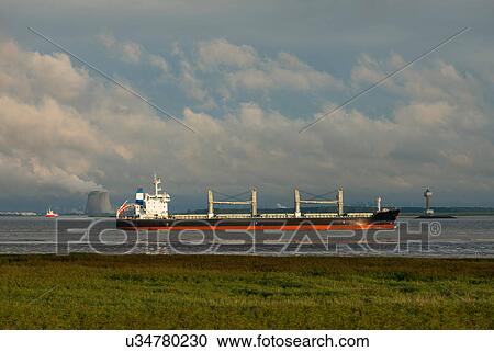 Stock Image - Ships sailing to and from Antwerp harbour. Nuclear power plant in the background, Rilland, Zeeland, Netherlands. Fotosearch