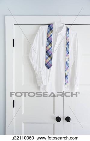Stock Image - Shirt and tie hang on closet door. Fotosearch