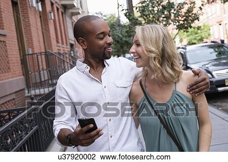 Stock Image - Smiling couple walking in residential district. Fotosearch