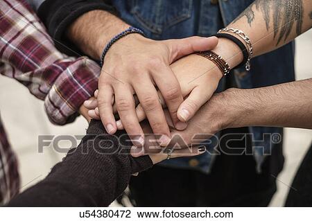 Stock Image - Stack of hands, friends holding hands outdoors. Fotosearch
