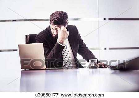 Stressed businessman with hand on forehead at office desk View Large Photo Image Stock Photo - Stressed businessman with hand on forehead at office desk. Fotosearch