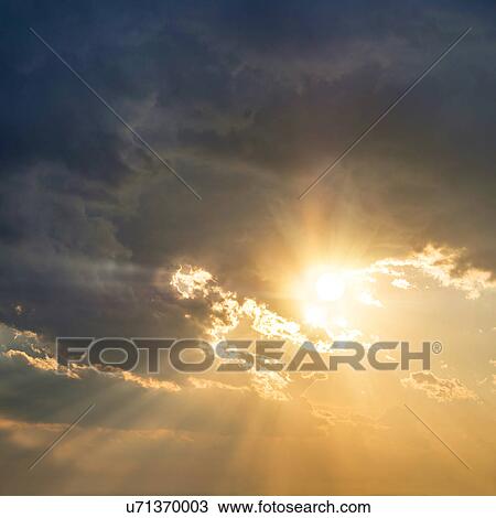 Stock Image - Sun breaking through clouds. Fotosearch