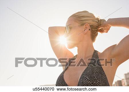 Sunlit portrait of woman tying hair in bun at beach, Alicante, Spain View Large Photo Image Stock Image - Sunlit portrait of woman tying hair in bun at beach, Alicante, Spain. Fotosearch