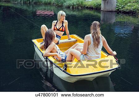 Stock Image - Three adult female friends in rowing boat on lake, Sattelbergalm, Tirol, Austria. Fotosearch