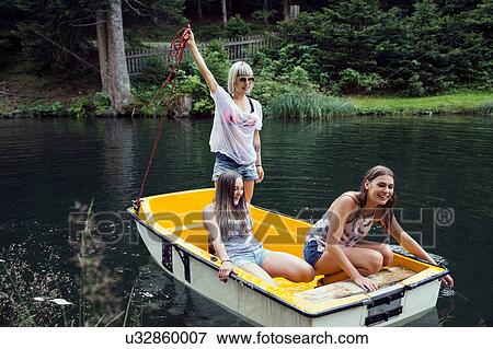 Stock Photo - Three adult female friends on rowing boat in lake, Sattelbergalm, Tirol, Austria. Fotosearch
