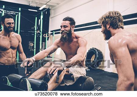 Stock Photo - Three male cross trainers chatting in gym. Fotosearch