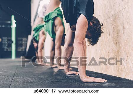 Stock Photo - Three male cross trainers doing handstands in gym. Fotosearch